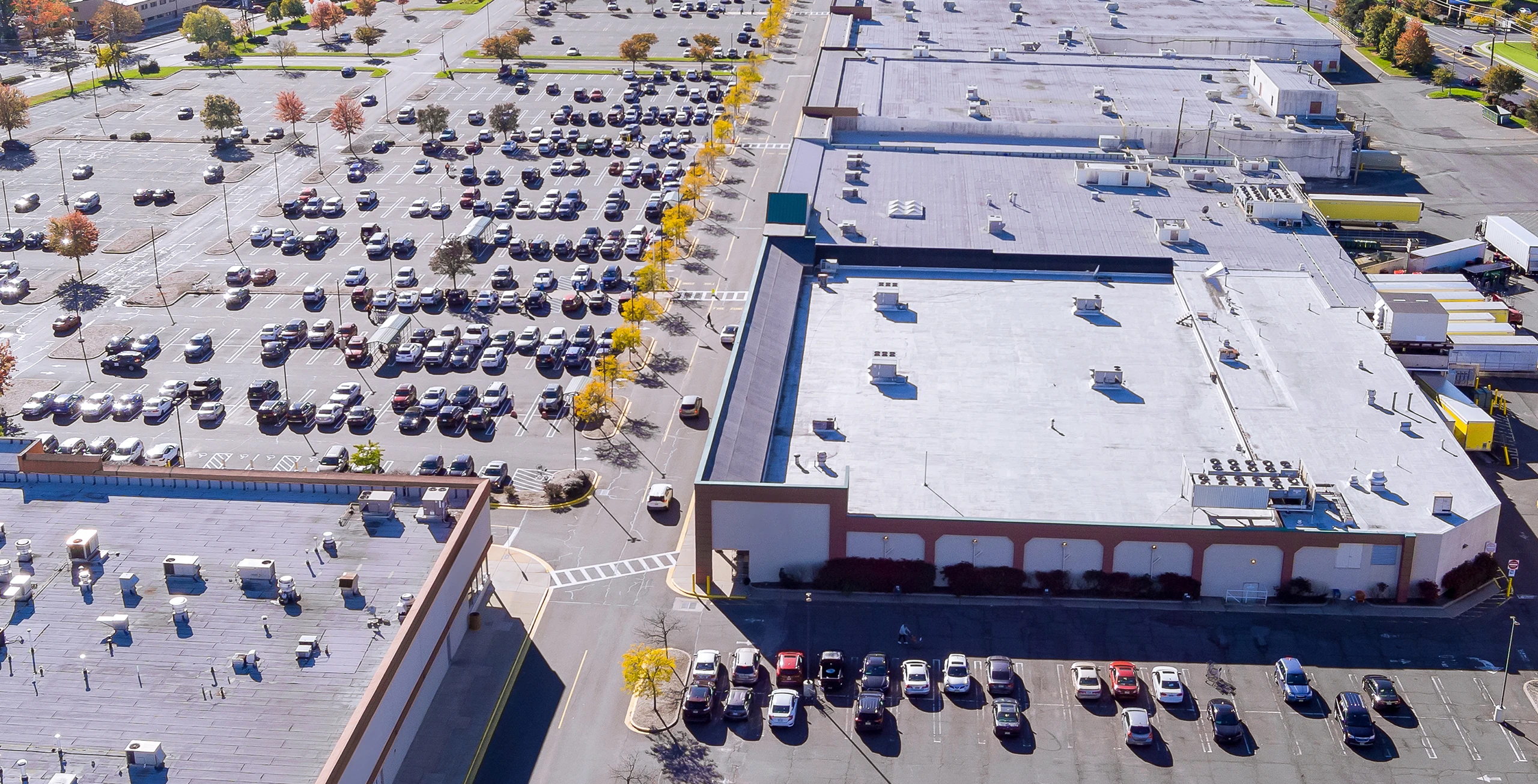 People walking inside a spacious, modern Gewerbe building with large windows and natural light streaming in.