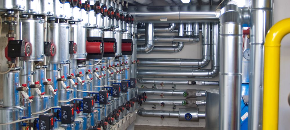 Ein Raum voller Rohre und Ventile in einem Gebäude, das für kommunale Rohrreinigungsprozesse oder Wassergewinnungsmethoden konzipiert ist.