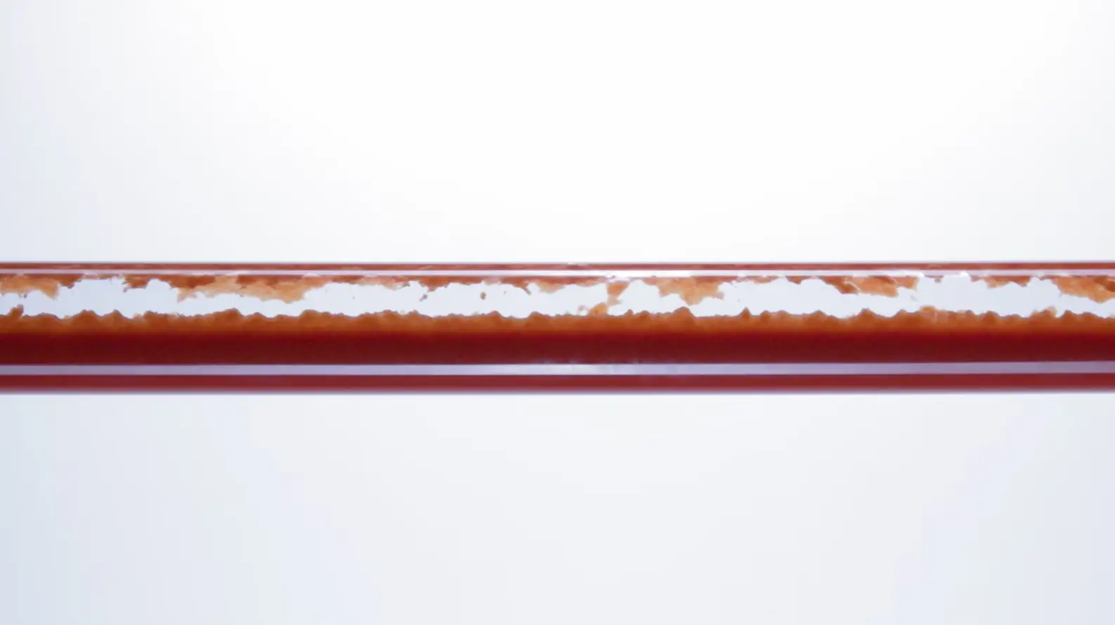 Close-up of a corroded or rusted pipe with visible build-up and deposits inside, highlighting the need for Comprex Reinigung solutions in the Industrie sector, against a plain white background.