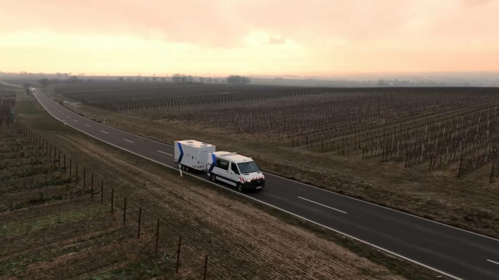 Ein weißes Wohnmobil fährt bei Sonnenuntergang unter einem bewölkten Himmel eine leere Landstraße zwischen Feldern entlang und erinnert an die Ruhe, die man nach einer gründlichen Rohrleitungs- und Anlagenreinigung mit Comprex® einstellt.